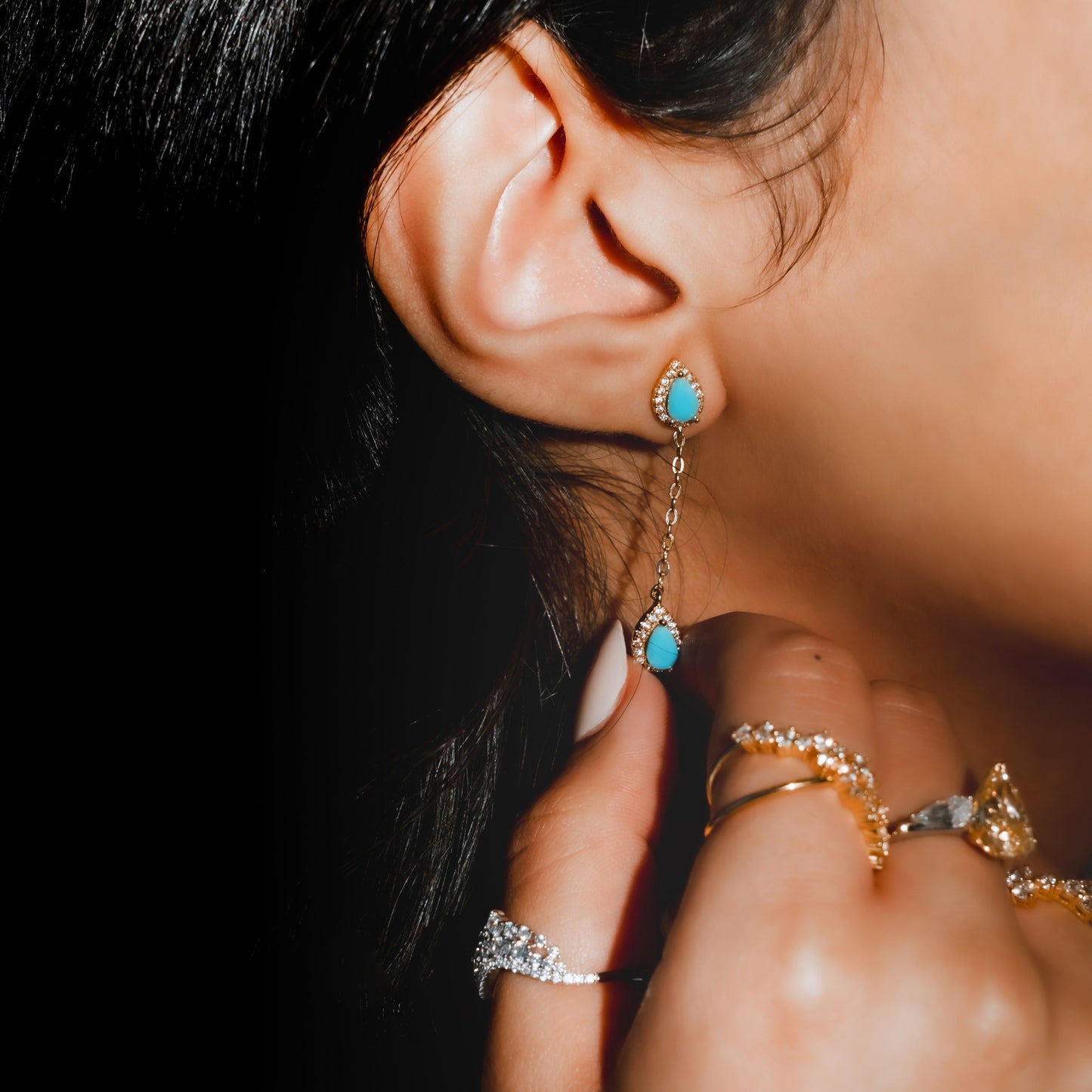Close-up of an ear wearing turquoise earrings with a blurred background