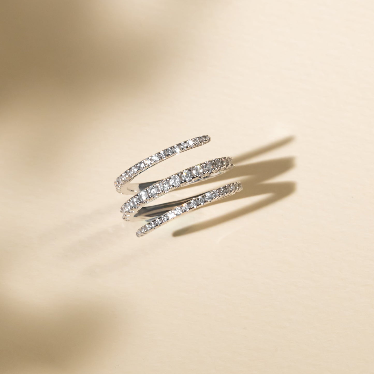 Two gold rings with diamond accents on a beige background