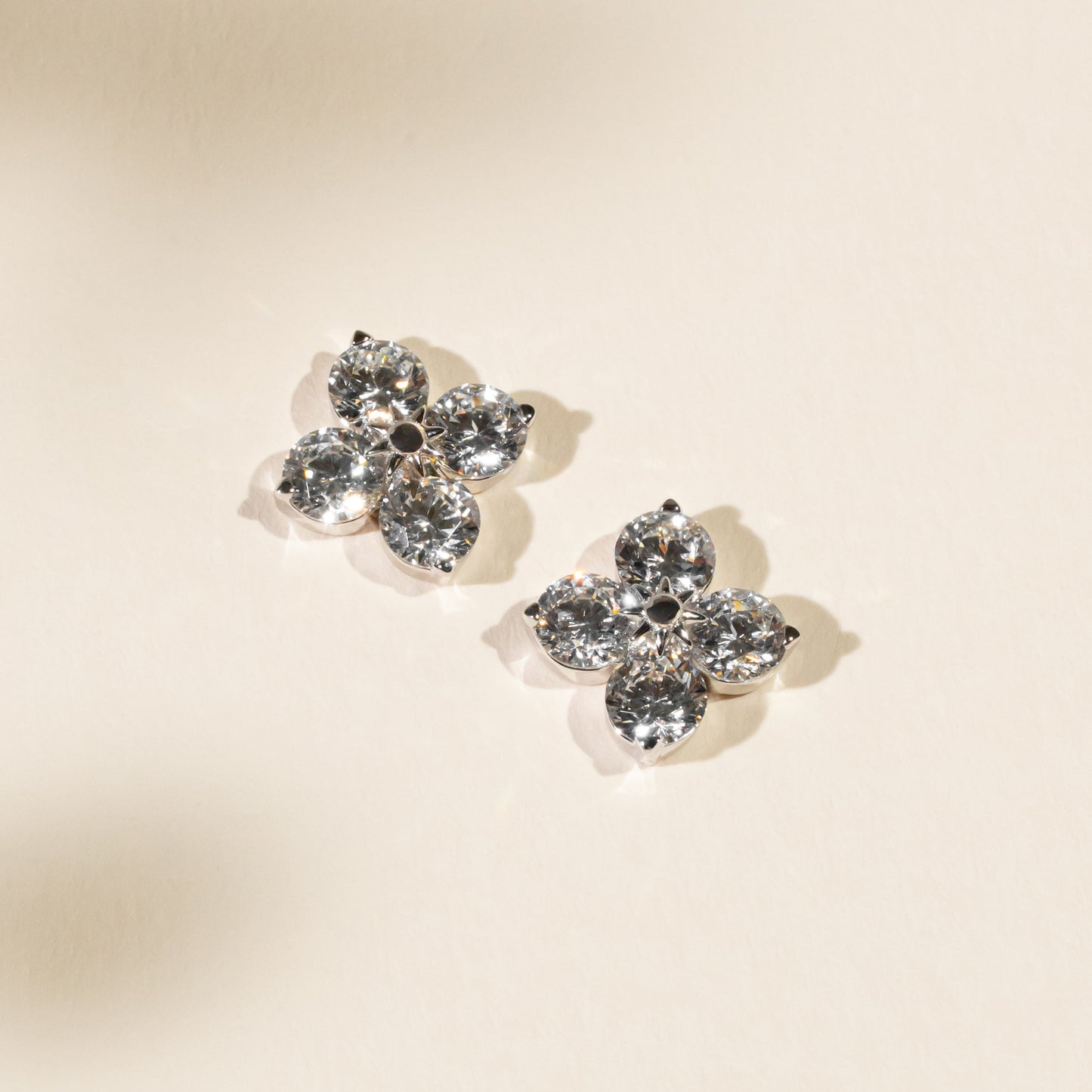 Pair of butterfly-shaped earrings with clear gemstones on a beige background